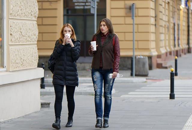 コーヒーを持ちながら歩く女性二人