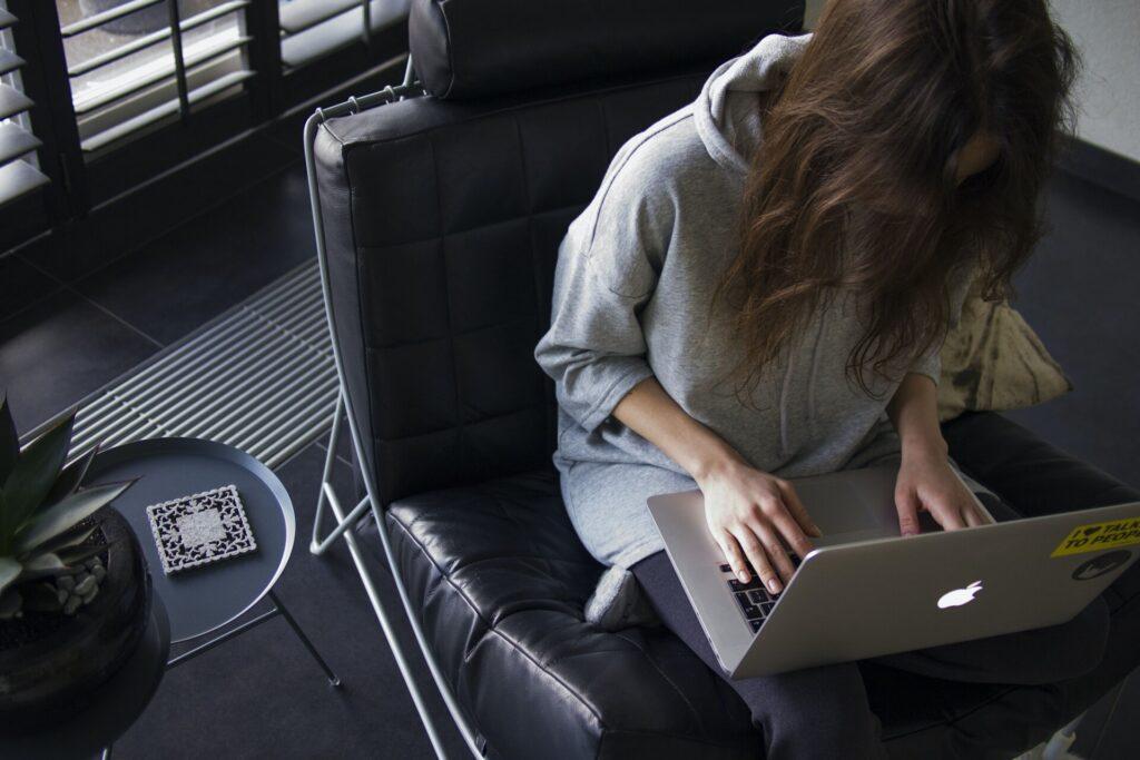 オフィスチェアに座りパソコンで仕事をしている女性